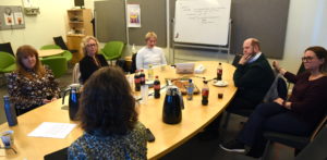 Noen av deltakerne i brukerrådet sitter rundt møtebord og diskuterer